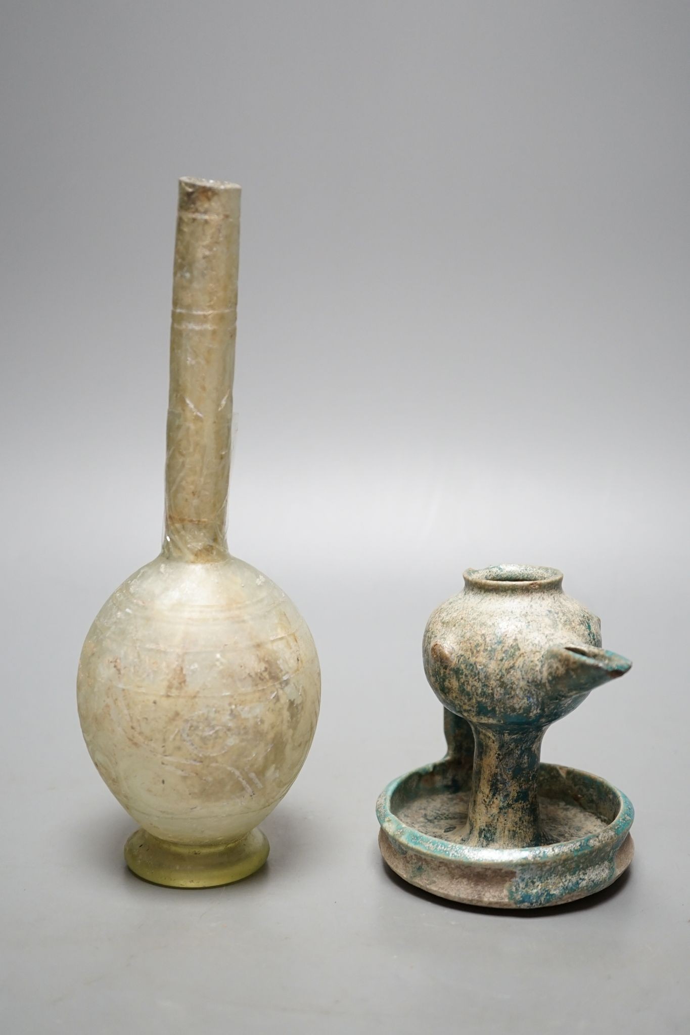 A Kashan oil lamp, 13th/14th century, and an early Islamic glass bottle., Bottle 22 cms high.